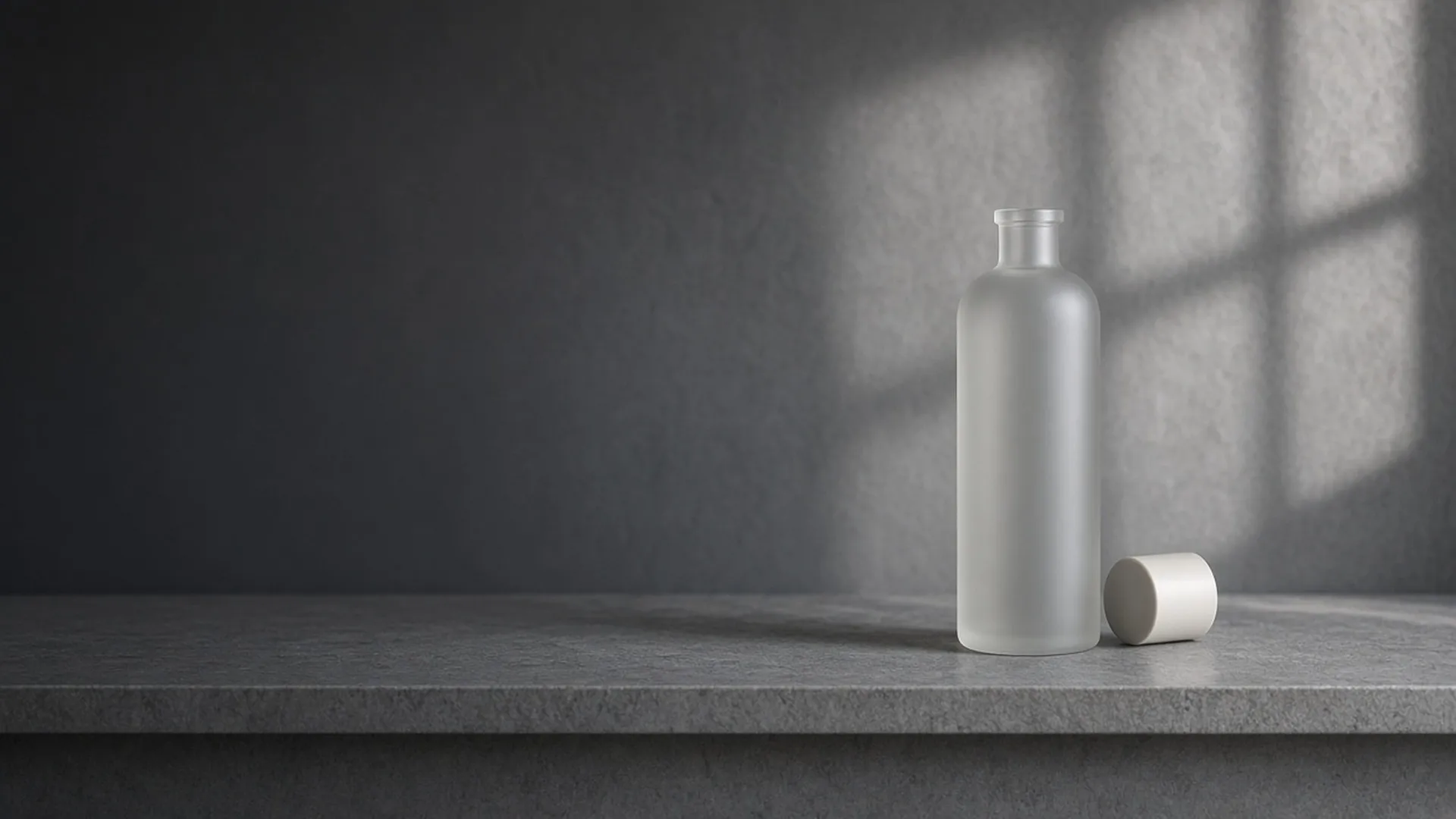 A plain bottle with its cap set aside on a shaded stone shelf
