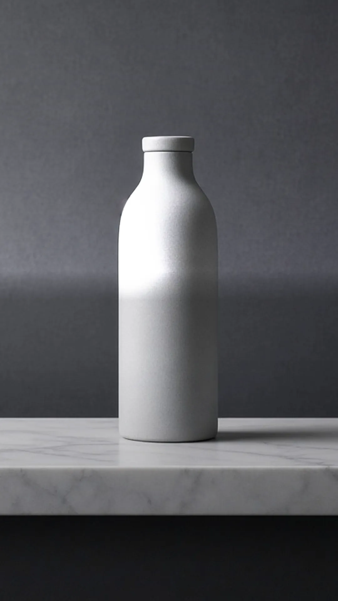A plain pale grey bottle standing alone on a smooth white marble ledge