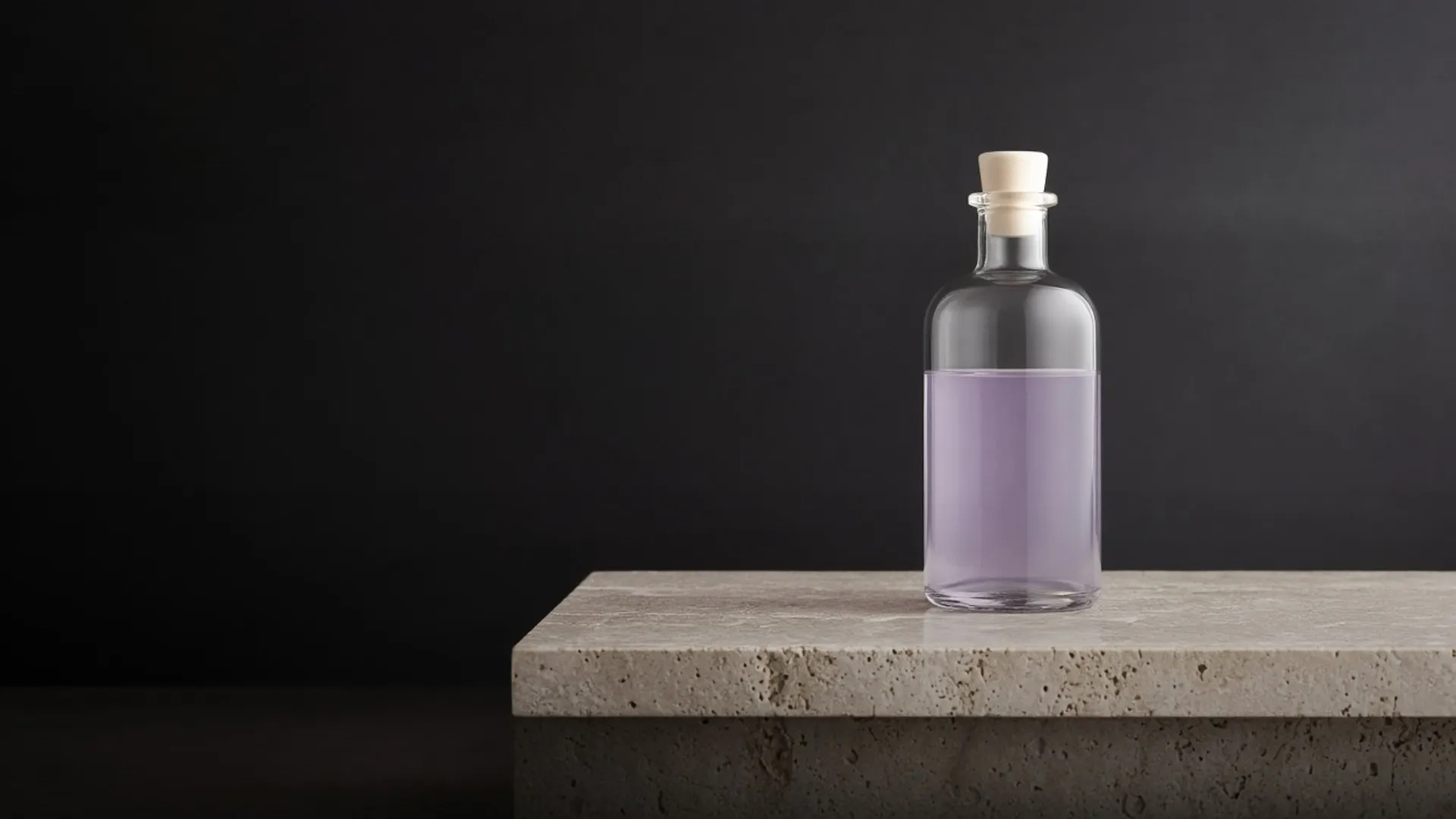 A clear unlabeled glass bottle of pale lilac liquid standing on a pale travertine ledge